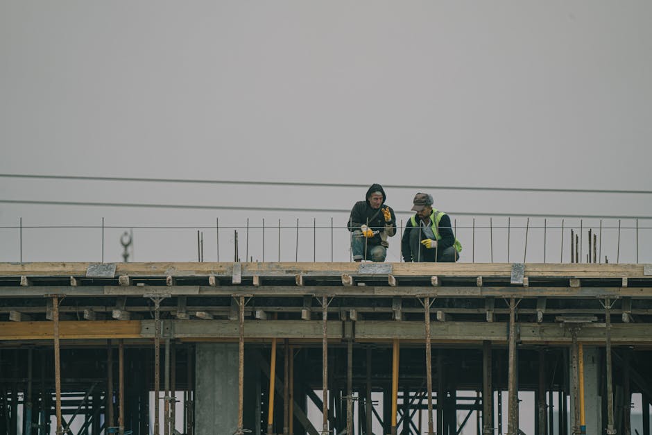Two construction workers on a building site in Denizli, Türkiye, working under overcast skies