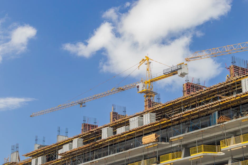 A modern construction site with cranes against a clear blue sky, showcasing urban development
